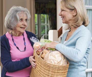 Female Neighbor Helping Senior Woman With Shopping