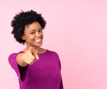 African american woman over isolated pink background points finger at you with a confident expression