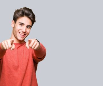 Young handsome man over isolated background Pointing to you and the camera with fingers, smiling positive and cheerful