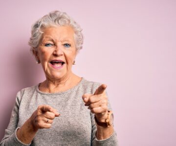 Senior beautiful woman wearing casual t-shirt standing over isolated pink background pointing fingers to camera with happy and funny face. Good energy and vibes.