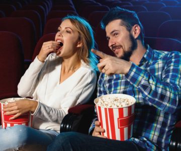 Attractive young caucasian couple watching a film at a movie theater